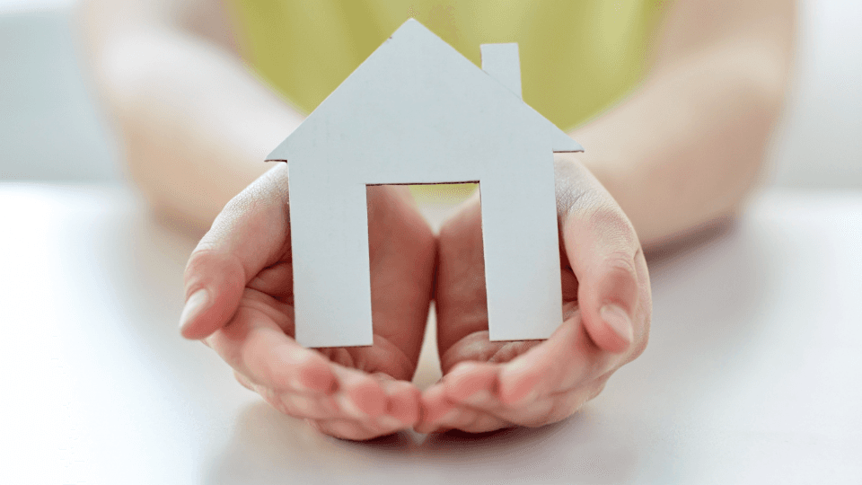 Woman's hands holding a paper house