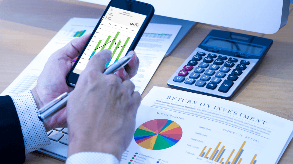 Man holding a phone with graphs and pen