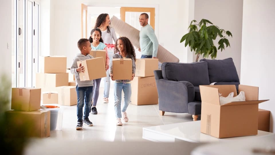 family walking through door with moving boxes