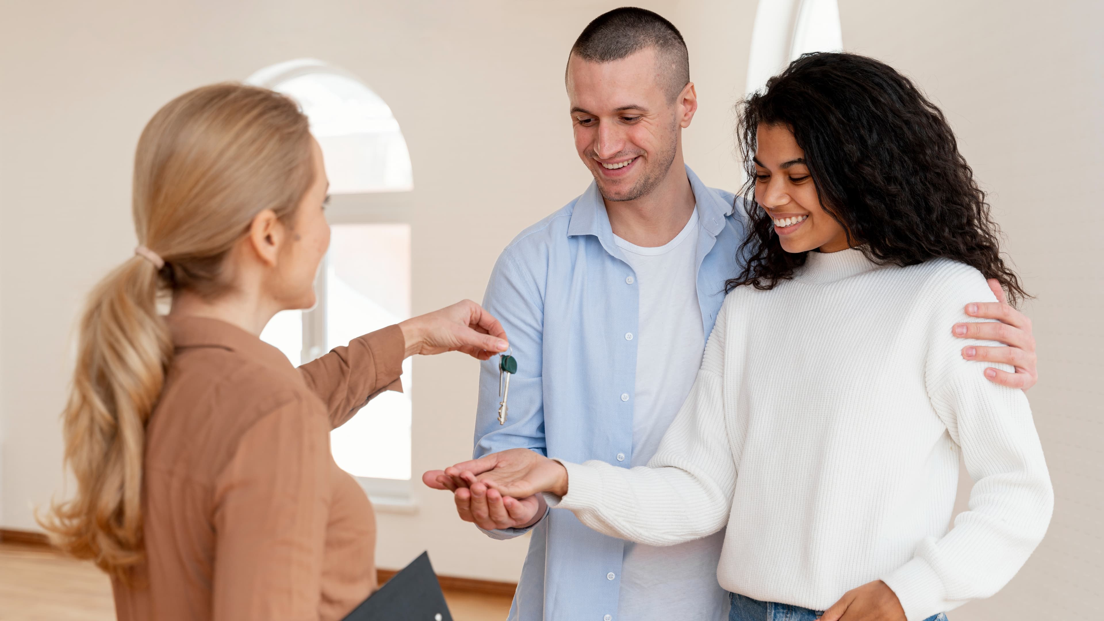 Realtor handing smiling couple keys to their new home